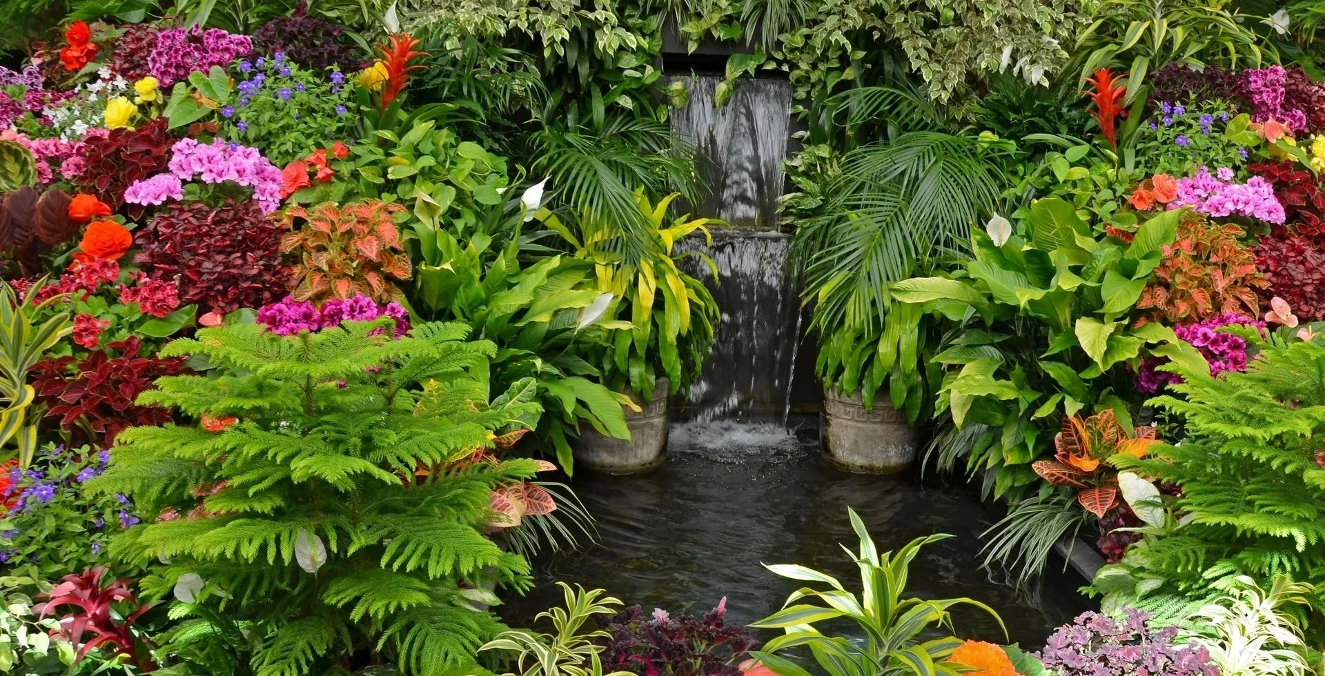 A waterfall surrounded by plants and flowers.
